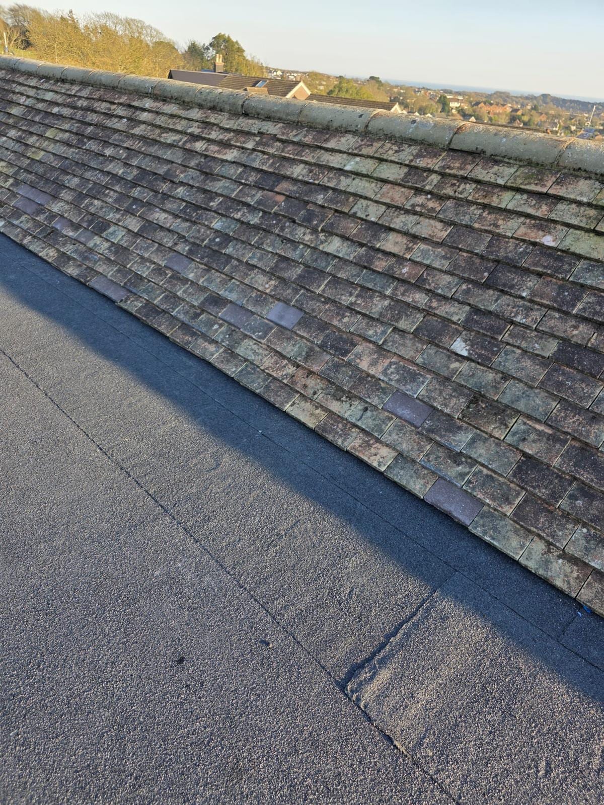 Finished torch-on felt flat roof beside a tiled roof