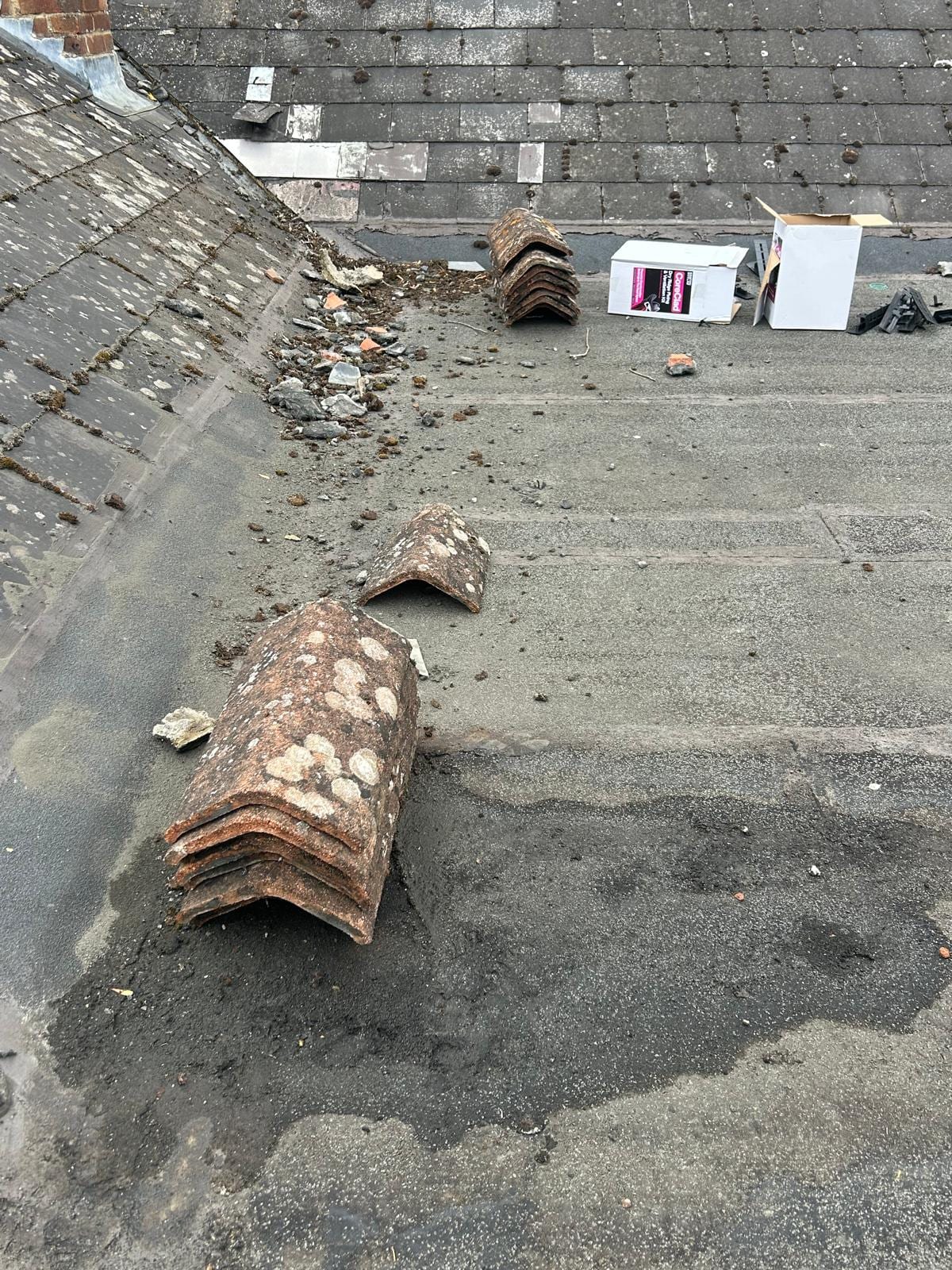 Old worn felt flat roof covered in debris and broken tiles